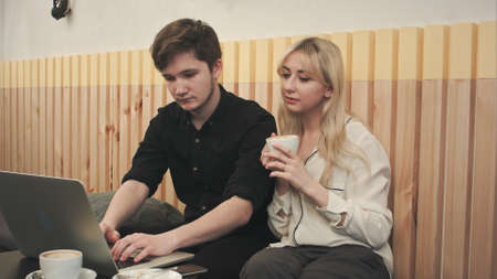 Couple working on laptop, drinking coffee at cafeの写真素材
