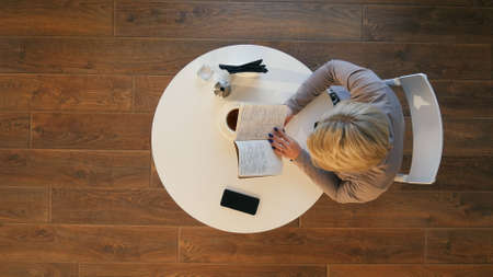 Sunday morning lifestyle scene of young hipster woman reading her notebook in cafeの写真素材