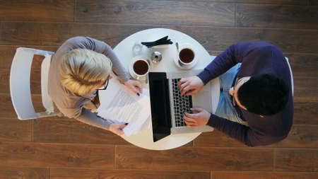Young business partners sitting at round table in cafe and working on projectの写真素材