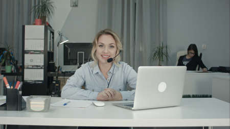 Smiling female consultant with headset presenting company servicesの写真素材