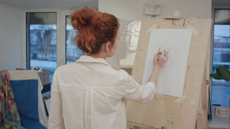 Female art student drawing plaster cast on easelの写真素材