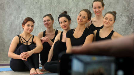 Male hand holding smartphone taking a photo of group of girls in fitness class at the breakの写真素材
