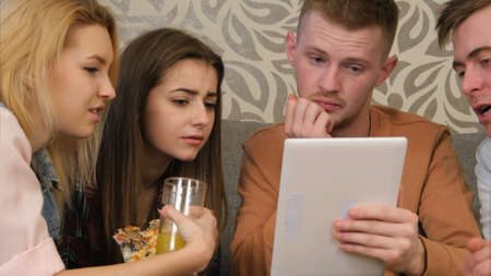 Friends watching comedy programm, using tablet, and laughingの写真素材