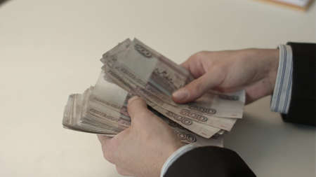 Businessman counts money in hands.