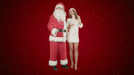 Christmas happy smile girl dancing with Santa Claus on red background with snowの写真素材