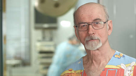 Senior mature surgeon smiling at the camera in hospital surgery examination roomの写真素材