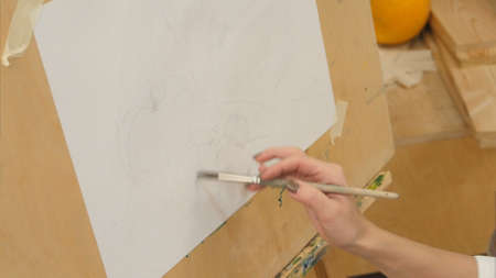 Female painter watering white paper on easelの写真素材