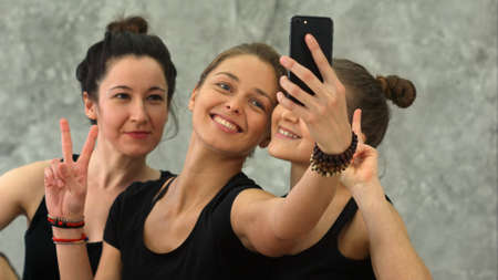 Three young women making selfie after workout at yoga class
