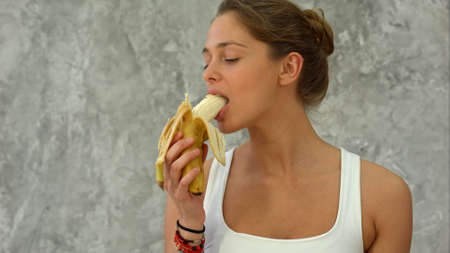 Attractive fit woman eating bananaの写真素材