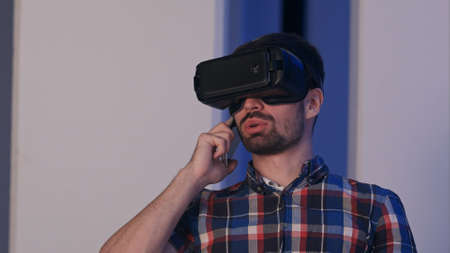 Smiling man in virtual reality glasses having conversation on the phoneの写真素材
