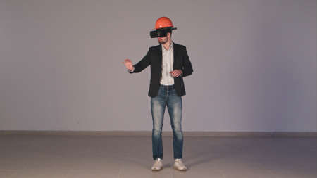 Young male engineer in hardhat with VR glasses designing construction projectの写真素材