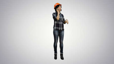 Young attractive asian engineer woman standing having a phone call on white backgroundの写真素材