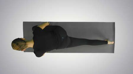 Young woman stretching body, looking at camera above on white backgroundの写真素材