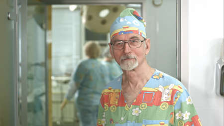 Smiling senior doctor looking at the camera in hospital surgery examination roomの写真素材