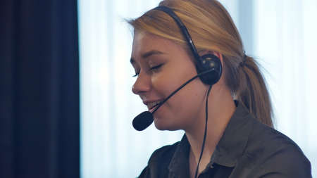 Female customer support operator with headset talking and smilingの写真素材