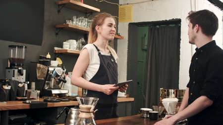 Male customer asking barista to make coffee in cafeteriaの写真素材