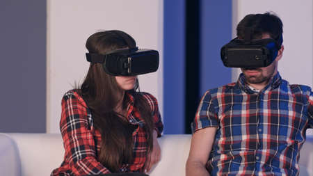 Young man and woman adjusting virtual reality glasses to watch movieの写真素材