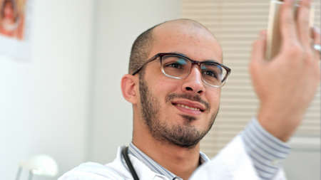Smiling male doctor taking selfies on his phoneの写真素材