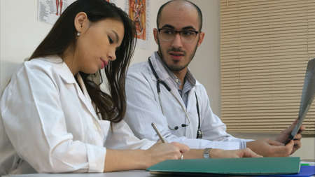 Male doctor teaching his female trainee how to analyze xray imageの写真素材