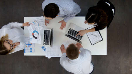 Ofice workers discussing business diagrams and wokring on laptopsの写真素材