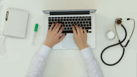 Female doctor hands typing on laptopの写真素材
