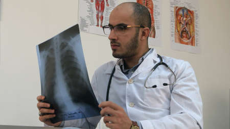 Concentrated young male doctor examining chest xray imageの写真素材
