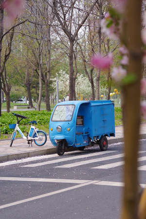 A blue electric scooter with a bicycle stands on the road in the city.
