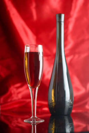 Red wine glass and bottle over red backgroundの写真素材