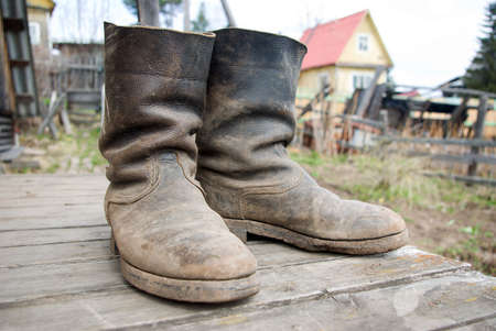 old muddy farmers boots on background wooden wallの写真素材