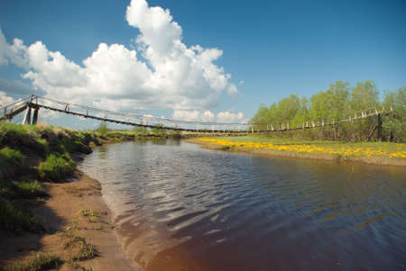 Suspension bridge over the river.Old Style Suspension Bridge -- crossing a mountain riverの写真素材