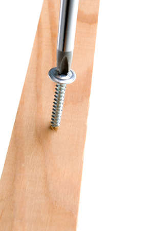 Screwdriver and single screw in board.a,isolated on white backgroundの写真素材