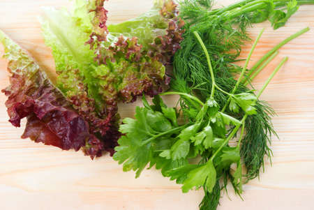 Salad,dill and parsley on wooden boardの写真素材
