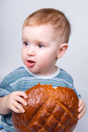 A little Caucasian boy eating a bread.big round loaf of bread of rustic bread
の写真素材
