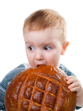 A little Caucasian boy eating a bread.big round loaf of bread of rustic bread 