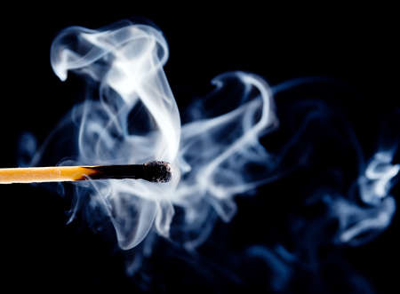 Wooden match burning on a black backgroundの写真素材