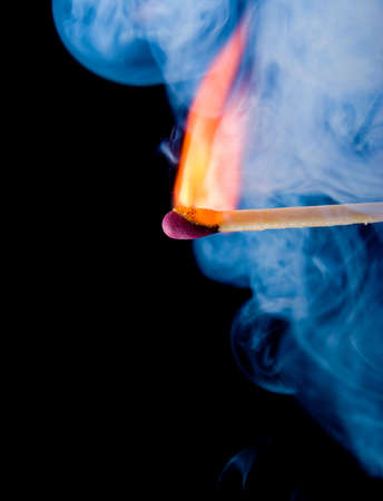 Burning match with blue smoke over black backgroundの写真素材