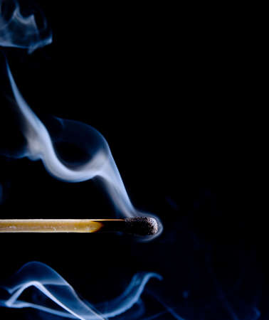 Wooden match burning on a black backgroundの写真素材