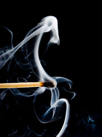 Wooden match burning on a black backgroundの写真素材