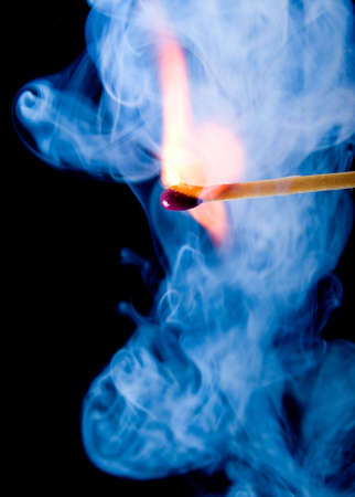 Burning match with blue smoke over black backgroundの写真素材