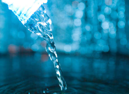 Bottle with creative splashing water.Macro of water poured into a glass of water の写真素材