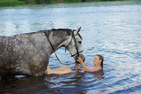 young woman swimming winth  stallion in riverの写真素材