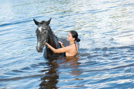 young girl bathe horse in a riverの写真素材