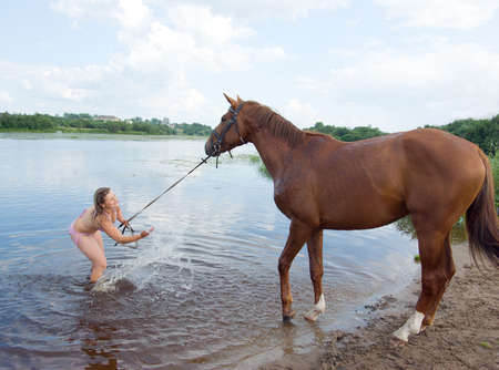 young girl bathe horse in a riverの写真素材
