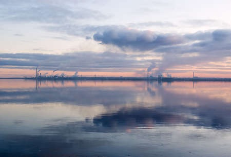 red sunset looms over largest paper factory.mirror image in riverの写真素材