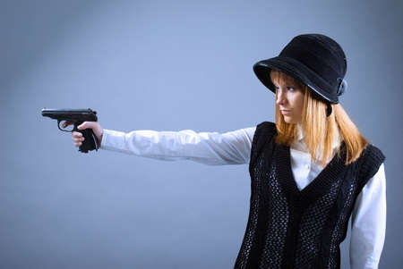 blonde holding a gun .gray studio background の写真素材
