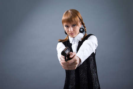 blonde holding a gun and aiming toward camera, focus on gun の写真素材