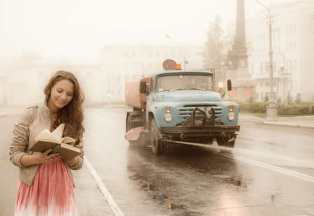 girl walks on town lonesome road and street sprinklerの写真素材