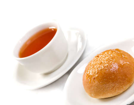 Tea cup and bun against white の写真素材