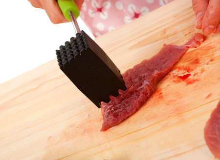 Closeup of cook hands making tenderized steak with meat hammer. 