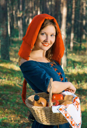 red Riding  hood standing in a wood . beautiful girl in medieval dressの写真素材